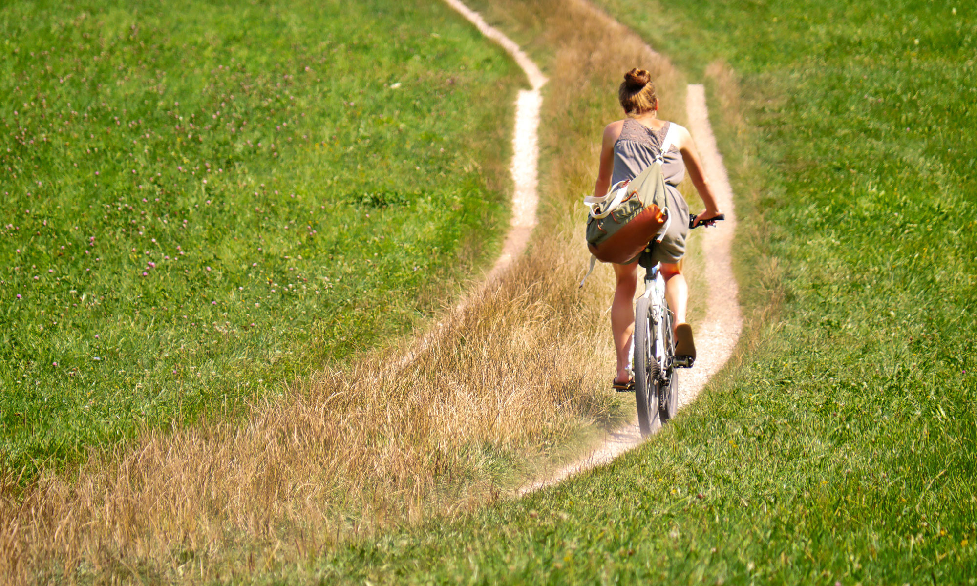Fahrradfahrerin auf einem Feldweg im Sommer; Fotograf fietzfotos, pixabay.com